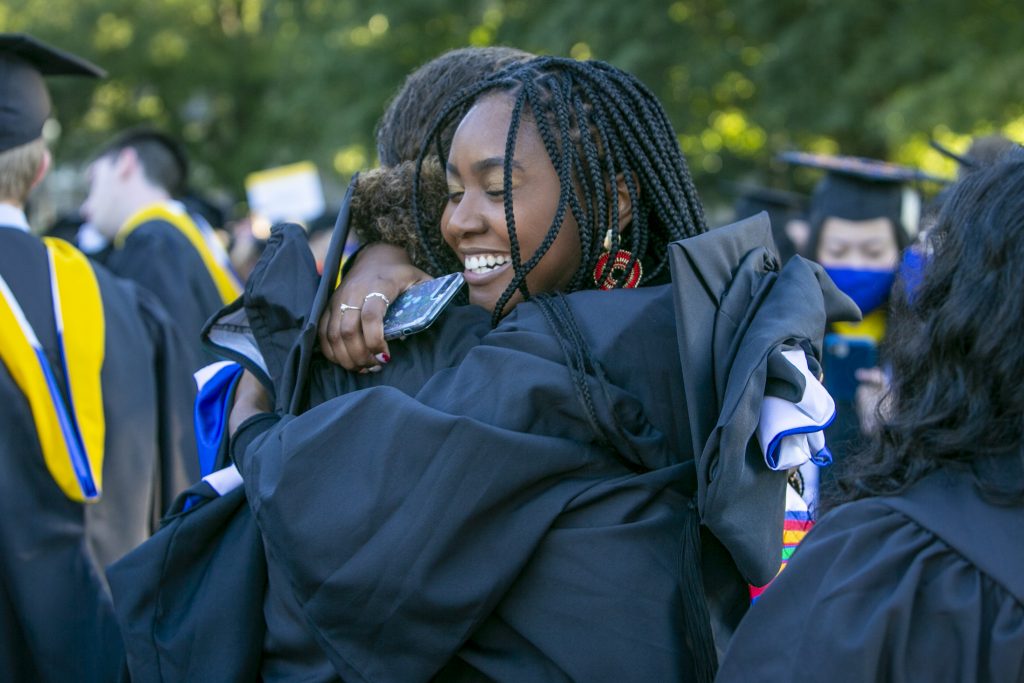 Two graduates embrace waiting in the line up to walk