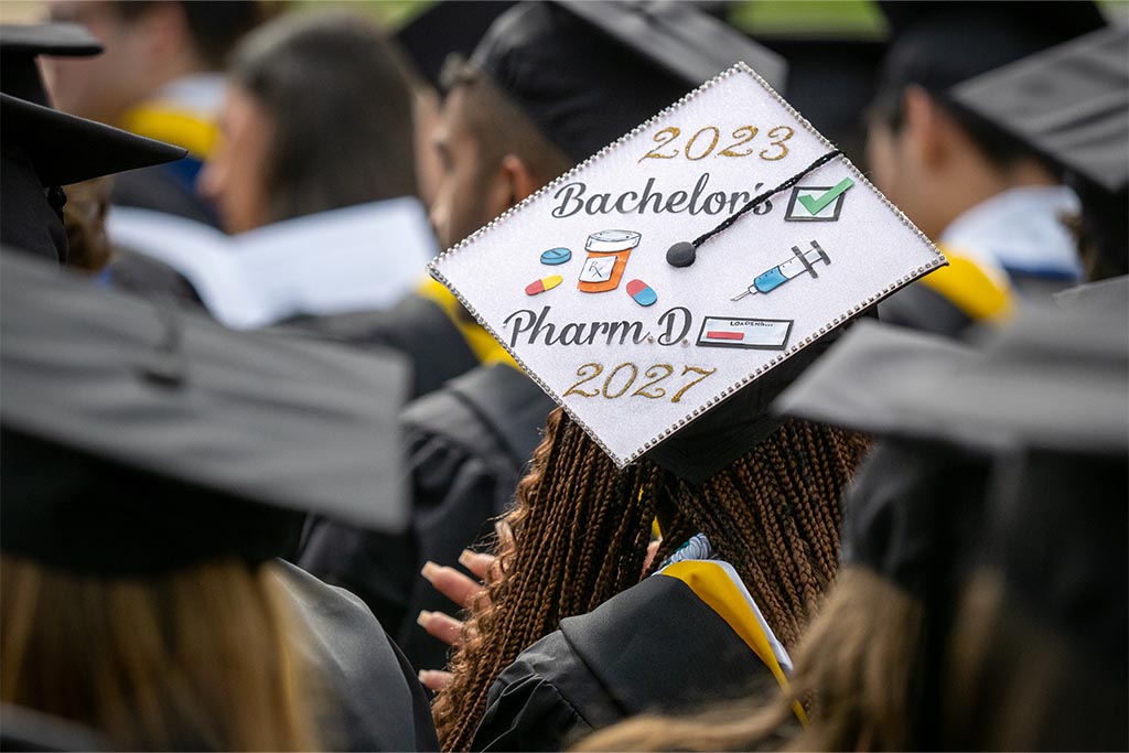 A mortarboard decorated with medicine related items like a pill bottle and syringe.