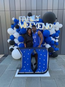Two people standing behind an Iron Duke D with balloons that spell out family weekend